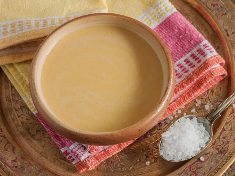 Herbata tybetańska w brązowej misce, obok łyżeczka z solą.