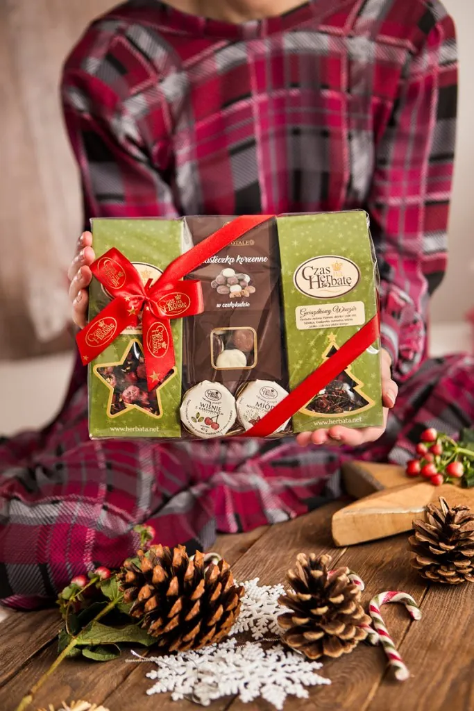 Osoba trzyma trójpak z herbatami oraz ciastkami korzennymi.