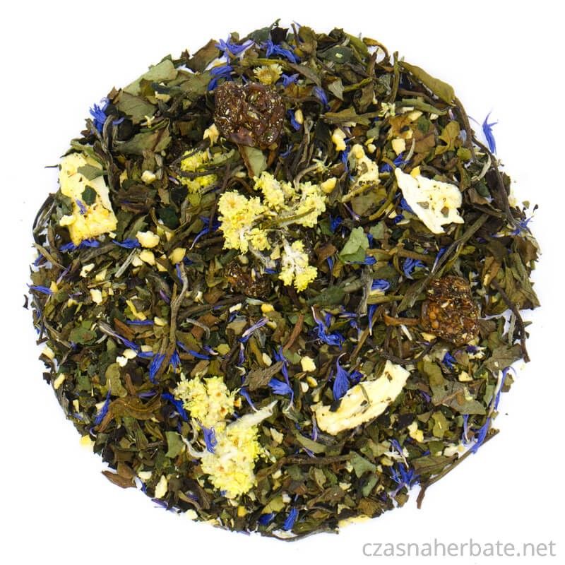 Mieszanka herbaty liściastej z kawałkami owoców, żółtymi i niebieskimi płatkami kwiatów oraz drobnymi dodatkami, widoczna na białym tle.