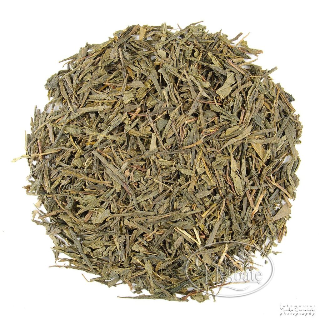 Na białym tle znajduje się herbata Bancha - jasnozielona, płasko cięta,z większmi liściami, charakterystyczna dla tej japońskiej zielonej herbaty.