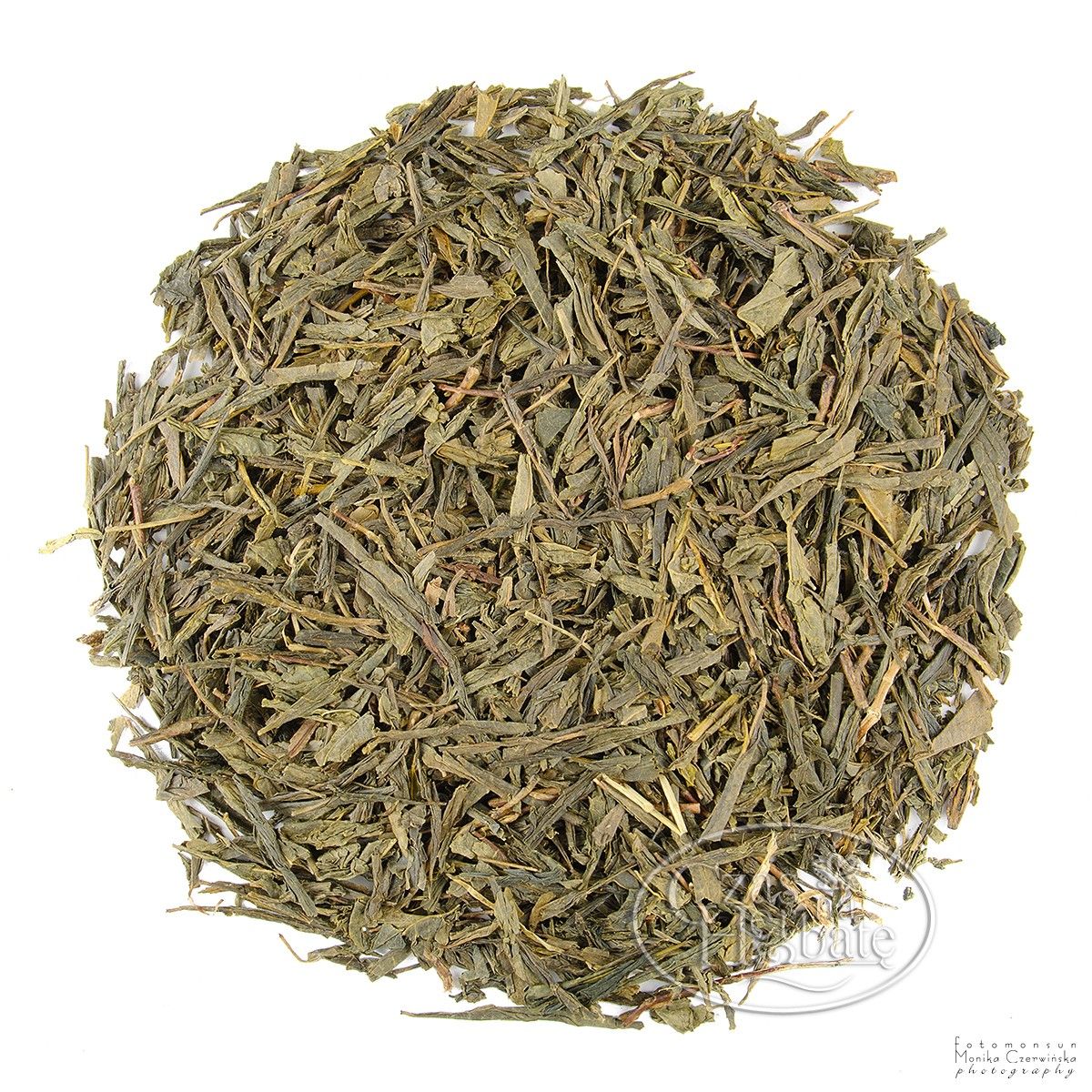 Na białym tle znajduje się herbata Bancha - jasnozielona, płasko cięta,z większmi liściami, charakterystyczna dla tej japońskiej zielonej herbaty.