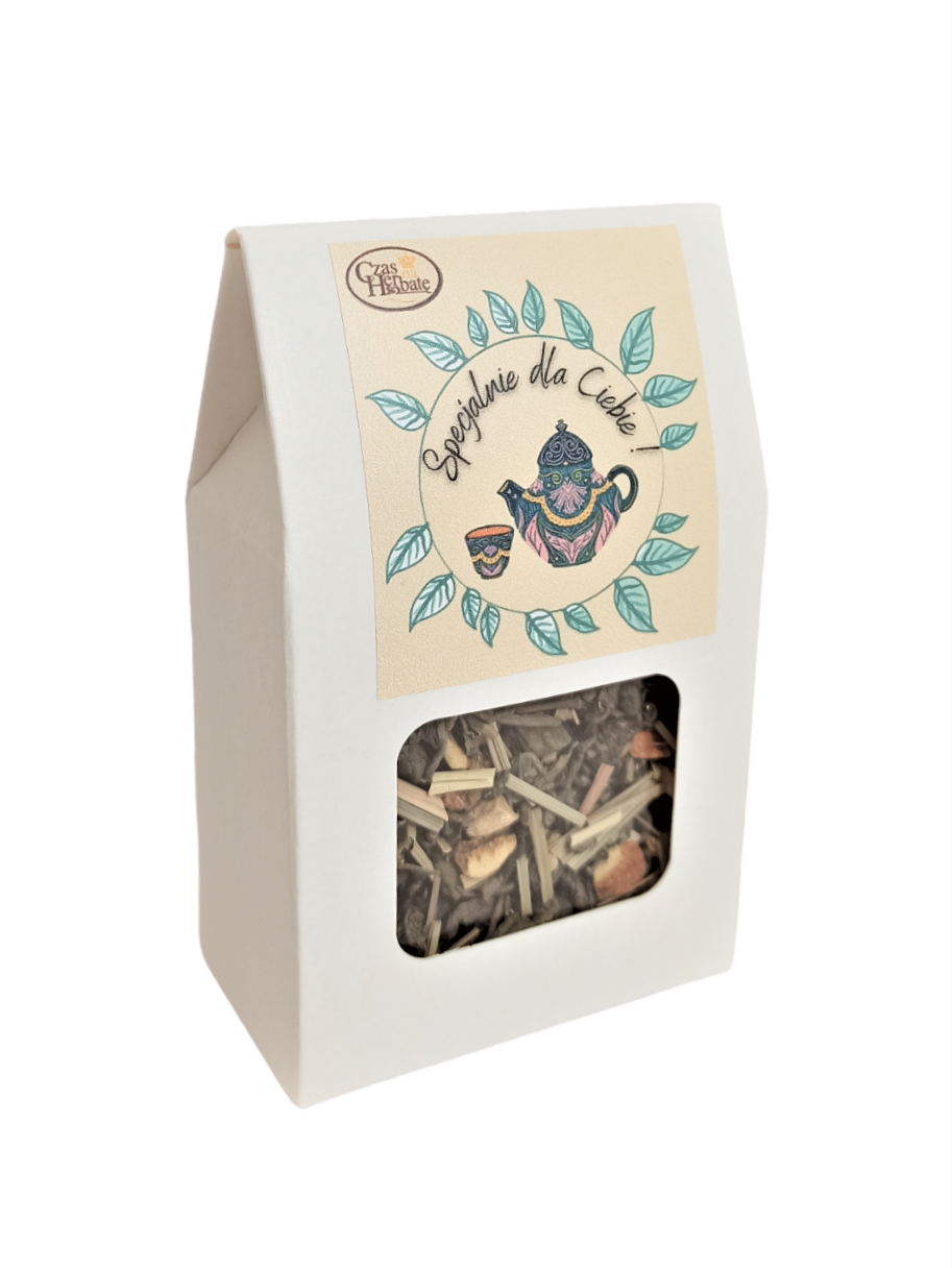 Widok z boku na jasne opakowanie z kwadratowym okienkiem i żółtą etykietą z rysunkiem wianka z liści