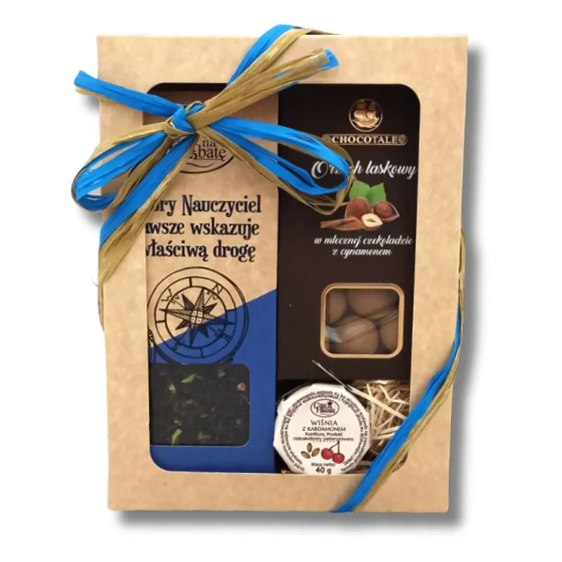 Beżowy kartonik z kwadratowym okienkiem i niebieską wstążką, w środku kartonik z herbatą, brązowy kartonik z orzechami laskowymi w mlecznej czekoladzie i słoiczkiem wiśni z kardamonem