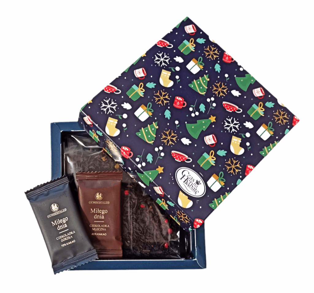 Otwarte kartonowe pudełko z motywem świątecznym, w środku: herbata liściasta z czerwonymi ziarenkami pieprzu oraz dwie czekoladki.