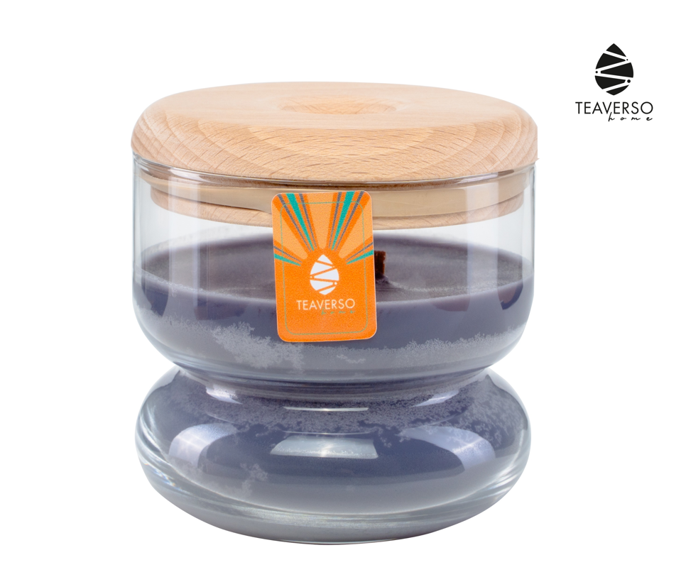 Fioletowa sojowa świeca zapachowa Teaverso Thalia czarna herbata w okrągłym szklanym słoiku z korkiem i pomarańczową etykietą.