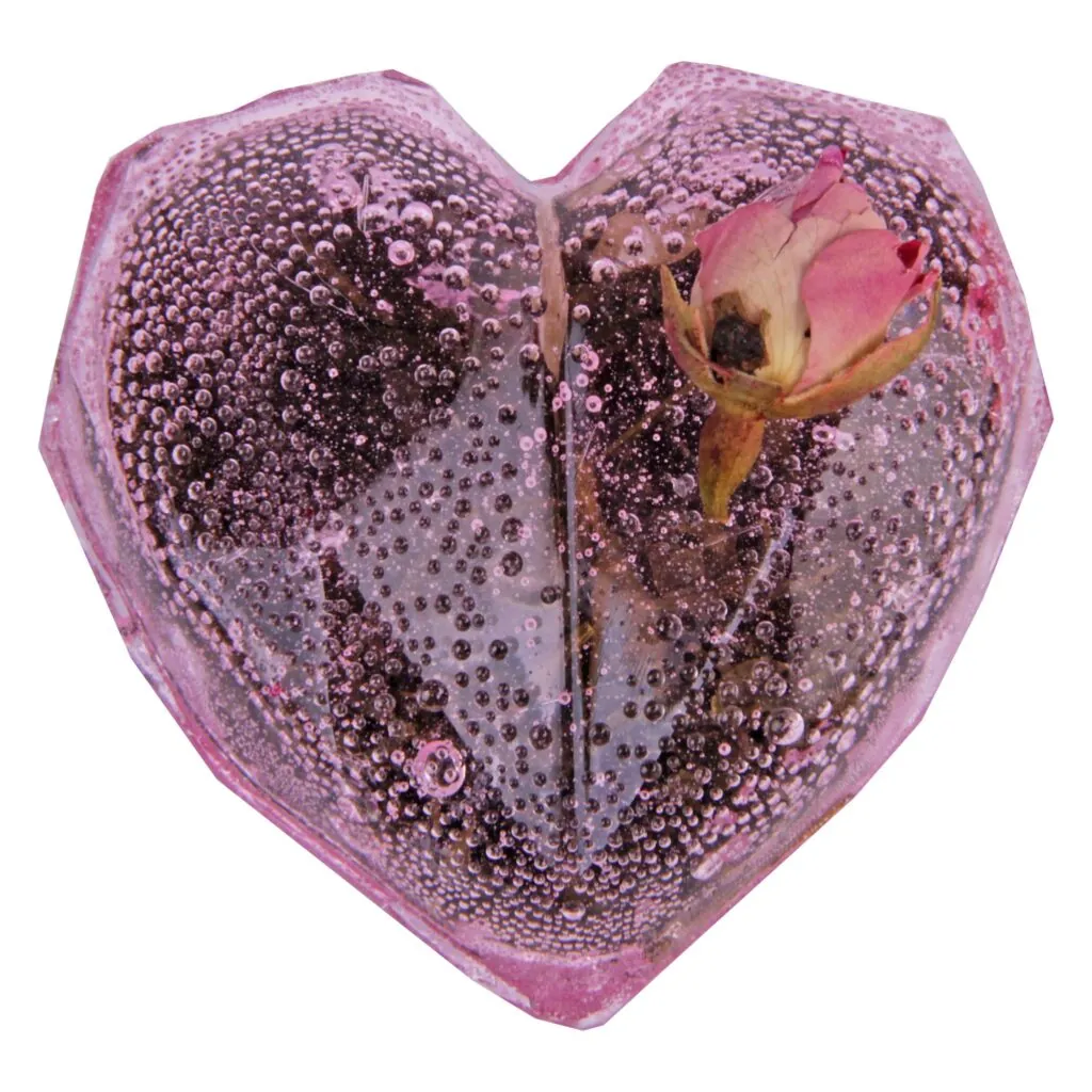 A pink heart-shaped tea ball with a sunken small rose bud, all covered with bubbles.