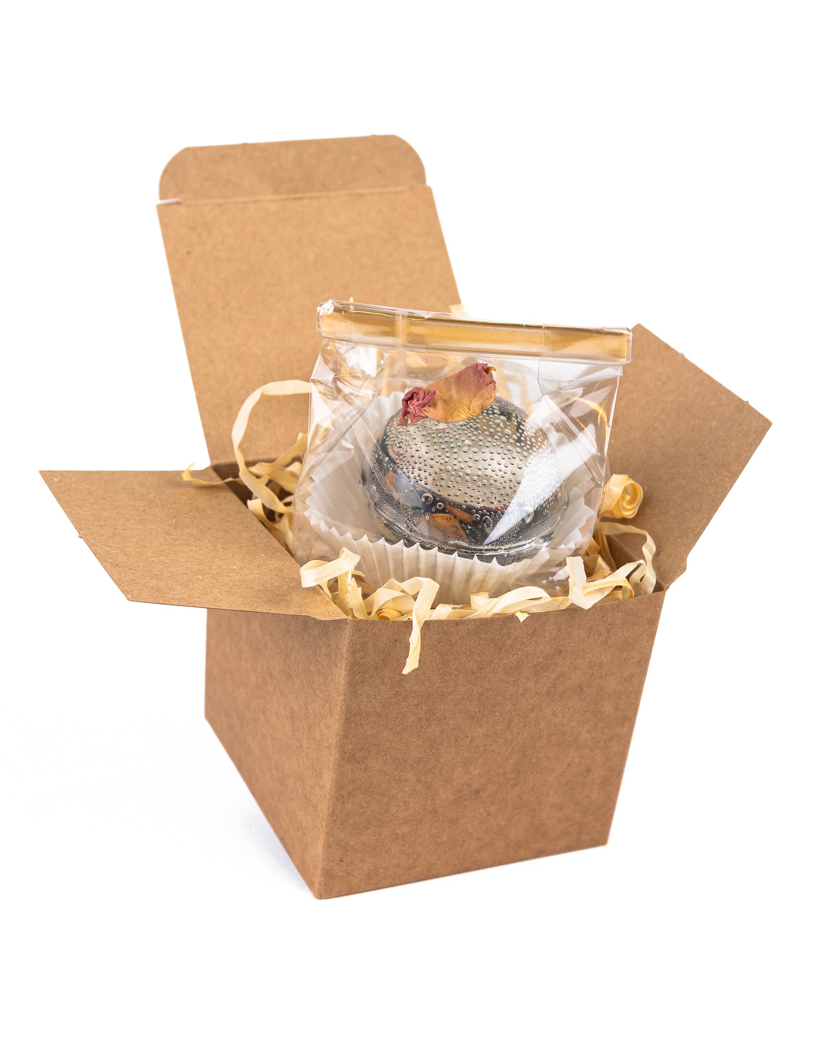 Kula kwiatowa do herbaty z płatkiem róży, zapakowana w celofan i ozdobne pudełko z siankiem dekoracyjnym.