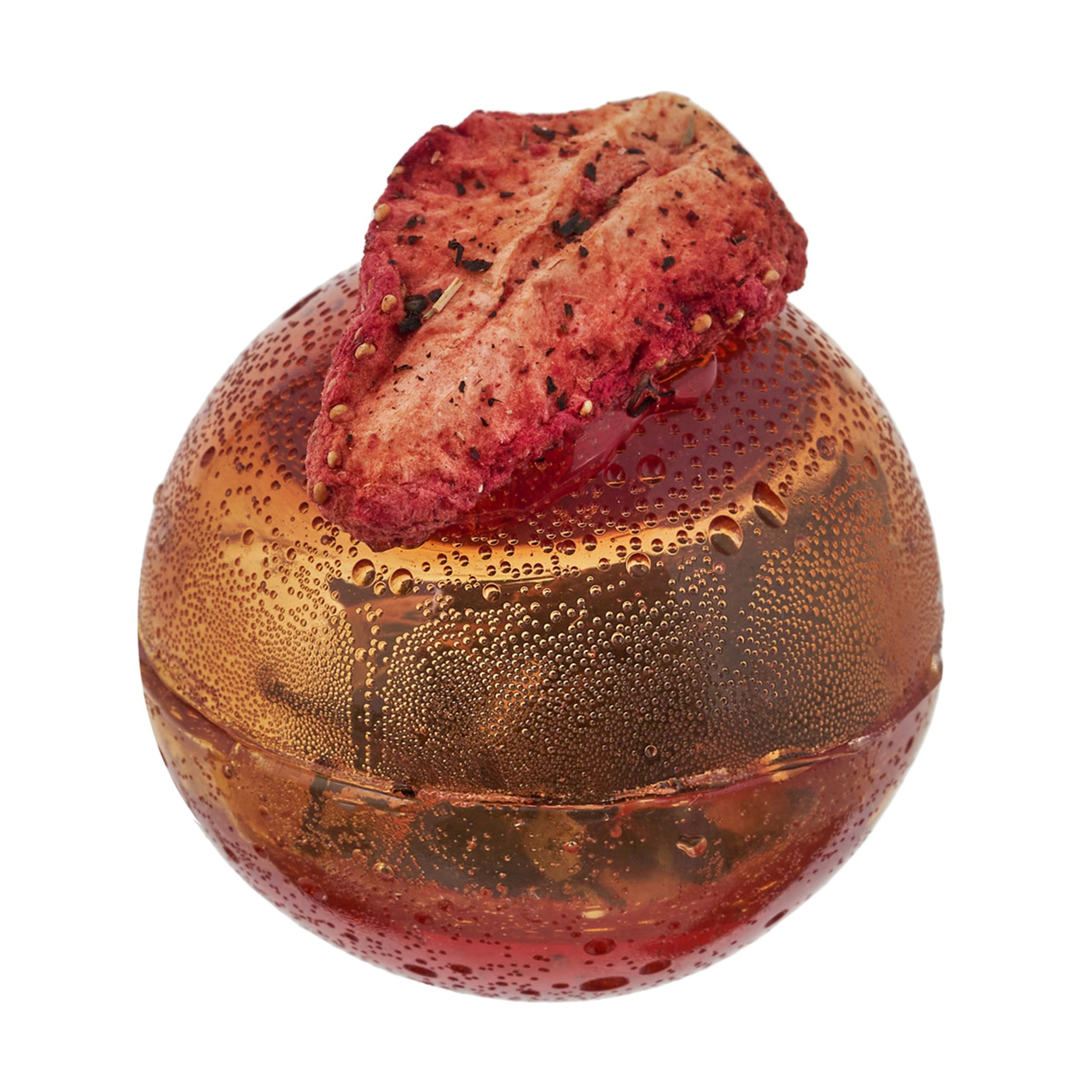 Kula kwiatowa do herbaty w kolorze bursztynowym z dużym liofilizowanym kawałkiem truskawki na szczycie.
