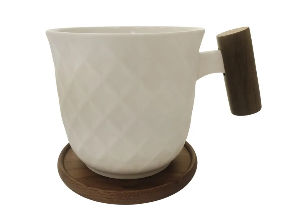 Biały kubek z geometrycznym wzorem, dużym drewnianym uchwytem i okrągłą podstawką.