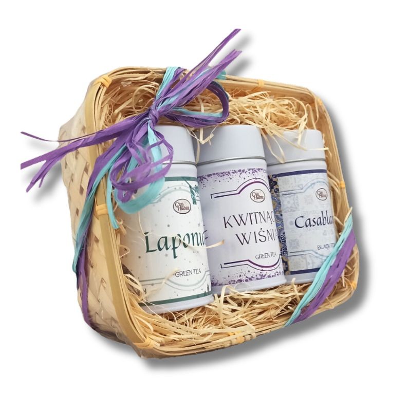 Widok z boku na zestaw prezentowy z trzema puszkami herbaty: Laponia, Kwitnąca Wiśnia i Casablanca, umieszczonymi w koszyczku z wstążką.