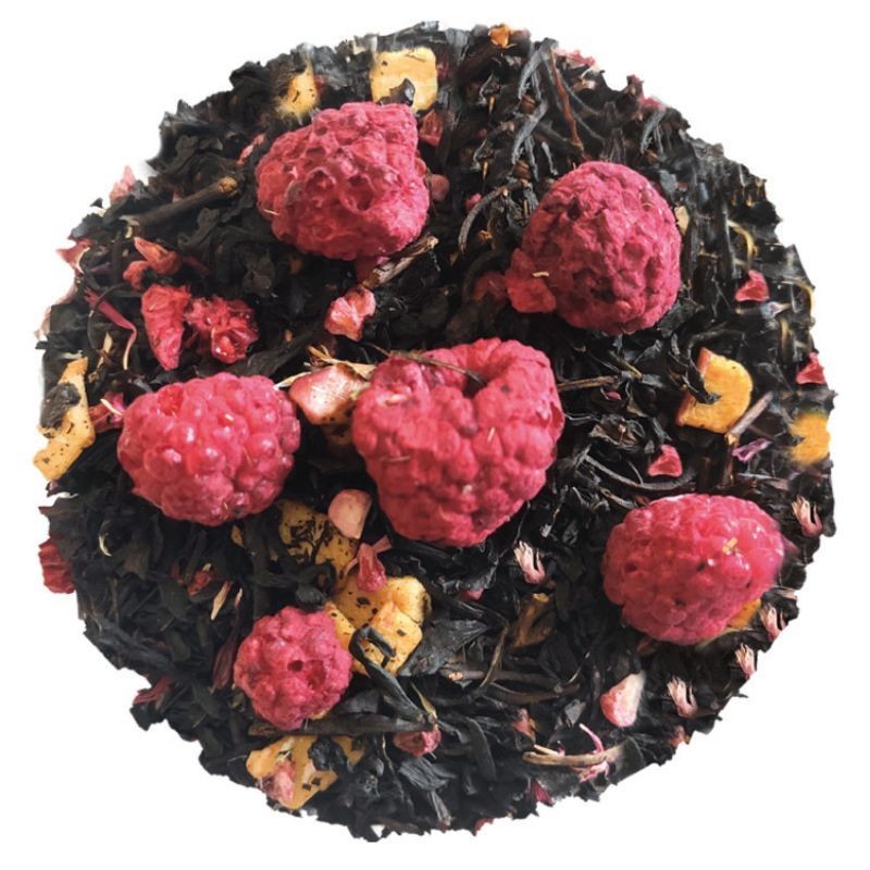 Liście czarnej herbaty z suszonymi malinami i kawałkami owoców, ułożone w okrąg na białym tle.