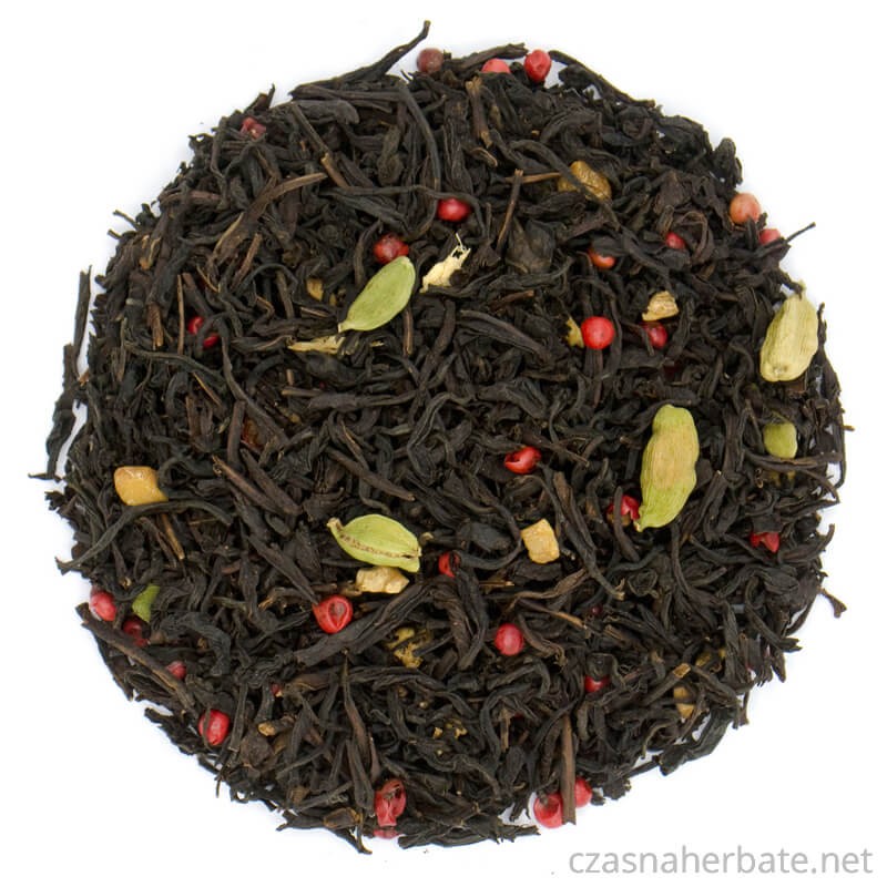 Black leaf tea with spices: cardamom pods, red pepper and small additions are visible, all on a white background.