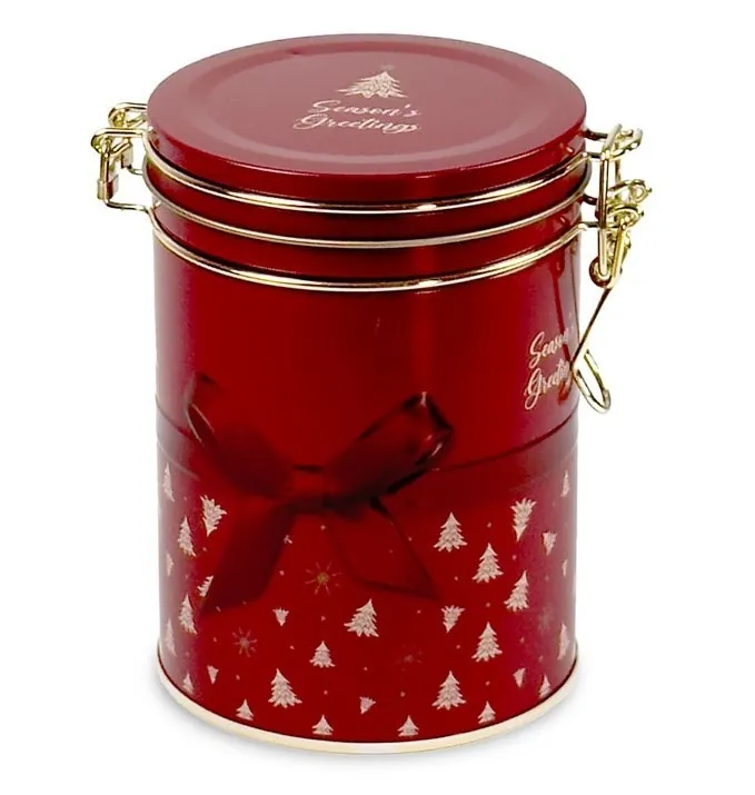 Okrągła, czerwona puszka z choinkami i napisem "Season's Greetings", zamykana na metalowe klamry, idealna na świąteczną herbatę.