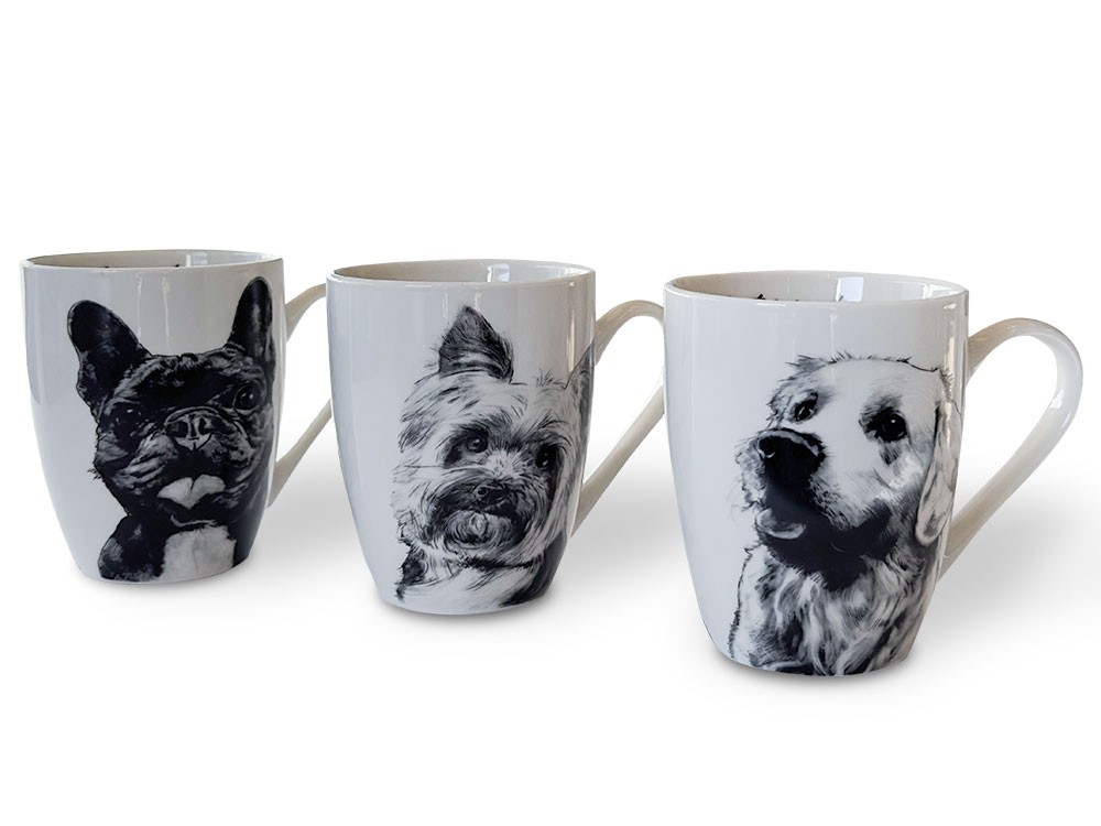 Three porcelain mugs with black and white drawings of dogs: a French bulldog, a yorkshire terrier and a golden retriever, set side by side.