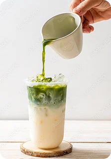 Nalewanie zielonej matchy z dzbanuszka do wysokiej szklanki z lodem i mlekiem.
