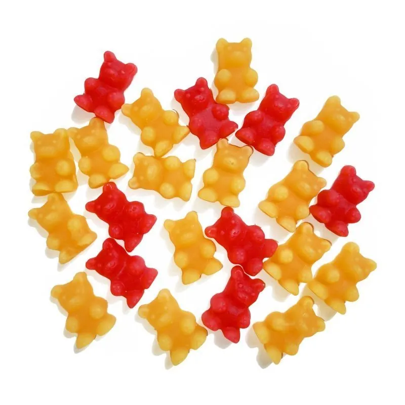 Czerwone i żółte żelki w kształcie misiów rozrzucone na białym tle.