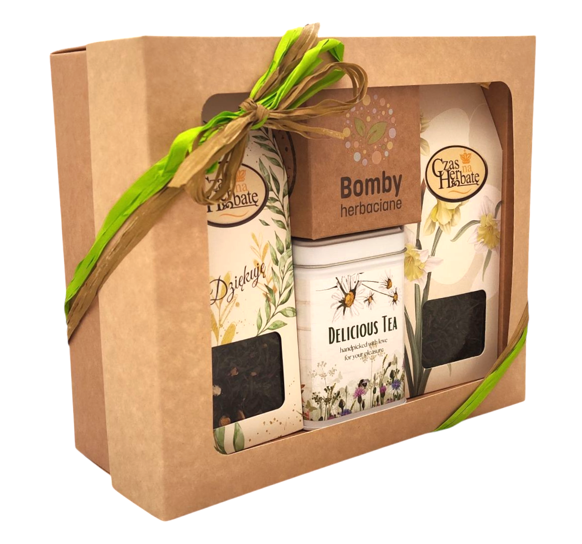 Widok z boku na zestaw „Herbaciana bomba” w pudełku z okienkiem, ozdobiony zielono-brązową wstążką; widoczne dwie herbaty, bomby herbaciane i puszka.