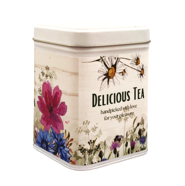 Kwadratowa puszka na herbatę z napisem „Delicious Tea”, ozdobiona kwiatowym motywem i pastelowymi ilustracjami polnych roślin.